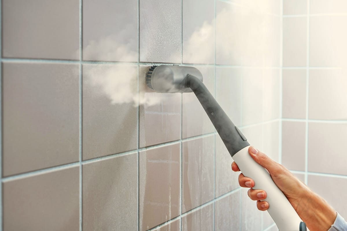 Steam cleaner sanitizing bathroom wall tile during a deep cleaning